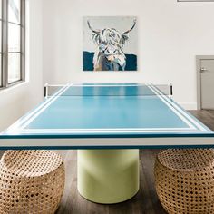 a ping pong table in the middle of a room with wicker stools