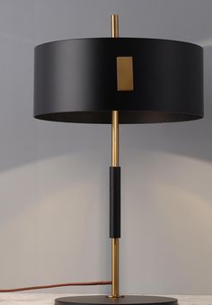 a black and gold lamp on a table with a white wall in the back ground