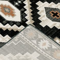 an area rug with different colors and patterns on it, including black, white, orange, and grey