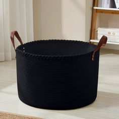 a large black basket sitting on top of a wooden floor