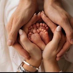 two people holding their hands together to show the baby's feet in its mother's lap