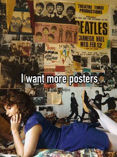 a woman laying on top of a bed next to a wall covered in posters