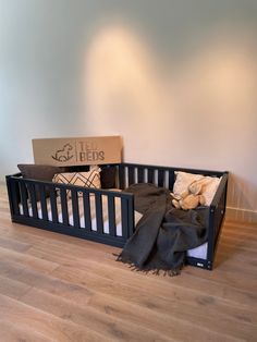 a baby crib with a blanket and stuffed animals in it next to a cardboard box on the floor