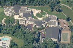 an aerial view of a large mansion with a tennis court in the middle of it