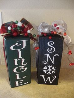 two black boxes with red and white bows on them, one is decorated like a christmas sign