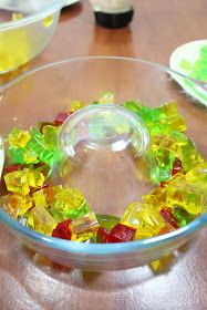 a glass bowl filled with gummy bears sitting on top of a wooden table next to other bowls