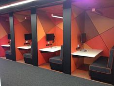 an office cubicle with multiple desks and chairs in the corner, all painted orange and black