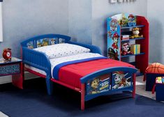 a child's bedroom with blue walls and red bedspread, toy shelves and toys