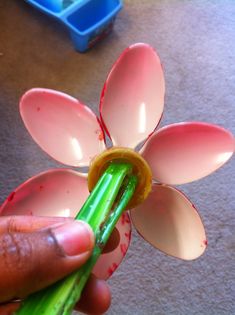 a person is holding a plastic flower with a green stick in it's hand