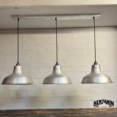 three pendant lights hanging from the ceiling over a wooden table