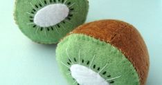 two stuffed kiwis are sitting on a white table top, one is green and the other is brown