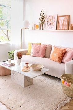 a living room with a white couch and pink pillows on the back of it's sofa