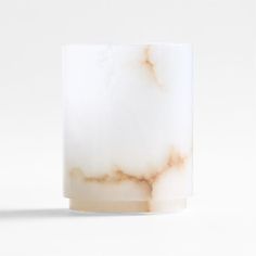 a white marble candle holder on a white background with the light reflecting off of it's surface