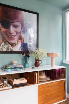 a painting hangs above a dresser in a blue room