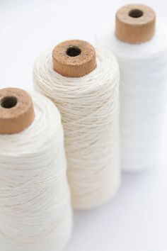 three spools of white yarn sitting next to each other