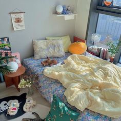 an unmade bed sitting next to a window with lots of clutter on it