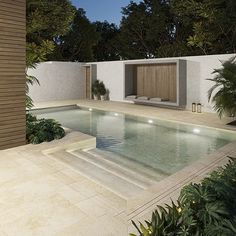 an outdoor swimming pool surrounded by greenery and trees at night with lights on the side