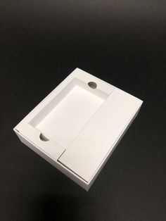 a white box with two holes in it on a black surface, the lid is open