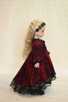 a doll with blonde hair wearing a red dress and black lace on it's head