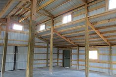 an empty building with lots of windows and wood beams on the ceiling, in front of two doors