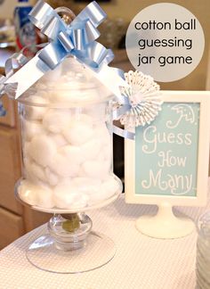 a glass jar filled with cotton balls on top of a table next to a sign