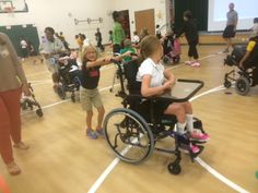 a group of people in wheelchairs on a basketball court with one person pointing at something