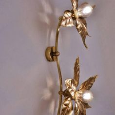 a wall mounted light with two flowers on it's arm and one flower in the middle