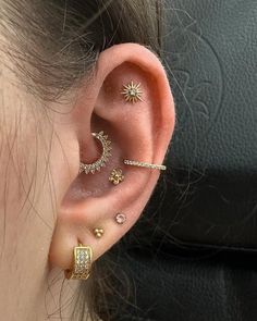 a woman wearing ear piercings with stars and moon designs on the side of her ear