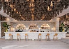 the bar is decorated with palm leaves hanging from the ceiling and wooden stools in front of it