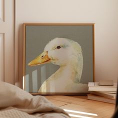 a white duck with yellow beak sitting in front of a framed photo on the wall