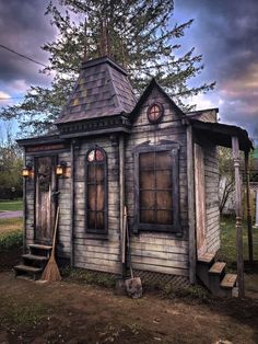 an old wooden house with a broom in front of it and a tree on the other side