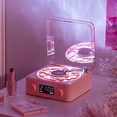 an electronic device is sitting on a table next to some lipstick and other cosmetics items