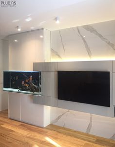 a fish tank sitting on top of a white cabinet next to a wall mounted tv