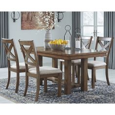 a dining room table with chairs and a bowl of fruit on top of the table