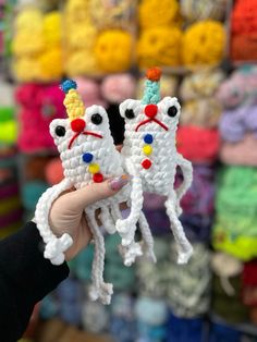 someone holding up two small crocheted unicorns