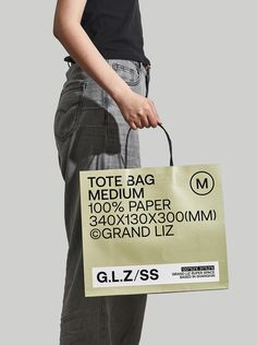 a person holding a paper bag in their right hand, with the text tote bag medium 100 % paper