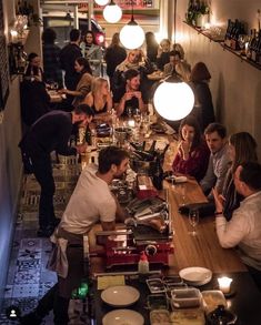 a group of people sitting at a long table in a restaurant with food on the counter