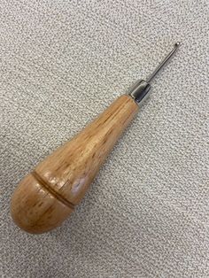 a pair of scissors sitting on top of a piece of wood next to a needle