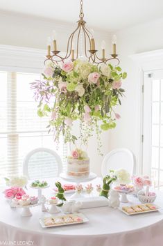 a white table topped with lots of food next to a chandelier filled with flowers