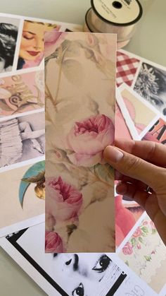 a hand holding up a piece of paper with pink flowers on it next to some pictures