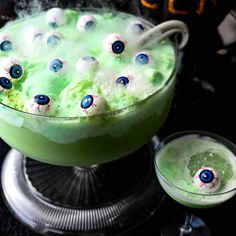 a green drink with eyeballs on it and a glass full of liquid next to it