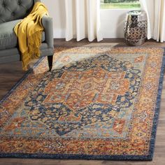 a large rug with an orange, blue and yellow design on the floor in front of a window