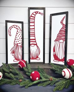 three red and white christmas decorations sitting on top of a table next to two framed pictures