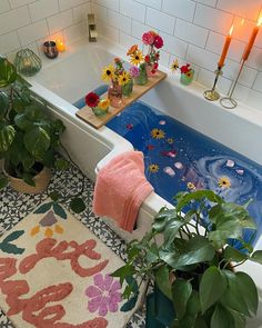 a bathtub filled with flowers and candles next to a rug in the middle of a bathroom