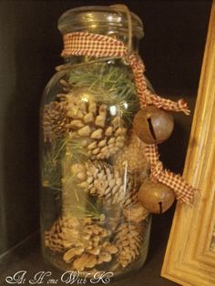 a glass jar filled with pine cones and other decorations