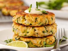 a stack of crab cakes on a plate with lemon wedges and garnish