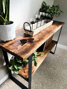 a wooden table with sunglasses on it next to a potted plant