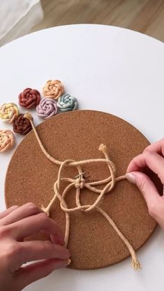 two hands are working on an art project with yarn and buttons in the shape of flowers