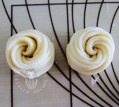 two cupcakes with white frosting sitting on top of a wire rack next to each other