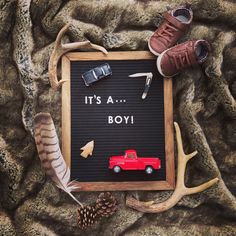 there is a sign that says it's a boy next to some shoes and antlers